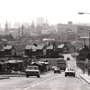A view of Byker taken in 1974. The photograph is looking towards Newcastle city centre. Buildings are in the process of being demolished on both sides of the road. The towers of St. Nicholas Cathedral All Saints Church and St. Ann's Church can be seen among the buildings in the background.