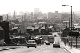 A view of Byker taken in 1974. The photograph is looking towards Newcastle city centre. Buildings are in the process of being demolished on both sides of the road. The towers of St. Nicholas Cathedral All Saints Church and St. Ann's Church can be seen among the buildings in the background.