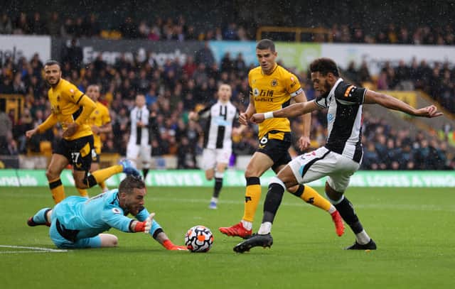 Joelinton of Newcastle United is challenged by Jose Sa of Wolverhampton Wanderers during the Premier League match between Wolverhampton Wanderers and Newcastle United at Molineux on October 02, 2021 in Wolverhampton, England. 