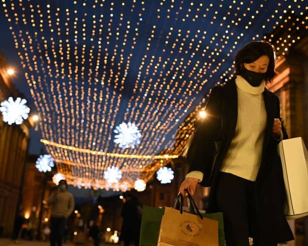 A shopper wearing a face mask or covering due to the COVID-19 pandemic, carries shopping bags through central Newcastle-upon-Tyne, in north-east England on December 19, 2020, on the last Saturday before Christmas. 