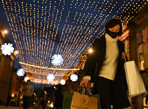 A shopper wearing a face mask or covering due to the COVID-19 pandemic, carries shopping bags through central Newcastle-upon-Tyne, in north-east England on December 19, 2020, on the last Saturday before Christmas. 