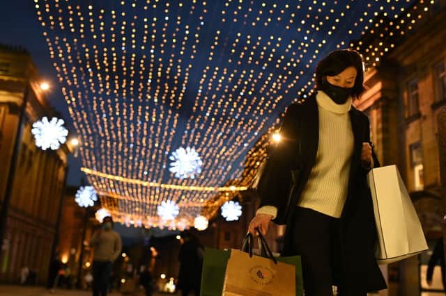 A shopper wearing a face mask or covering due to the COVID-19 pandemic, carries shopping bags through central Newcastle-upon-Tyne, in north-east England on December 19, 2020, on the last Saturday before Christmas. 