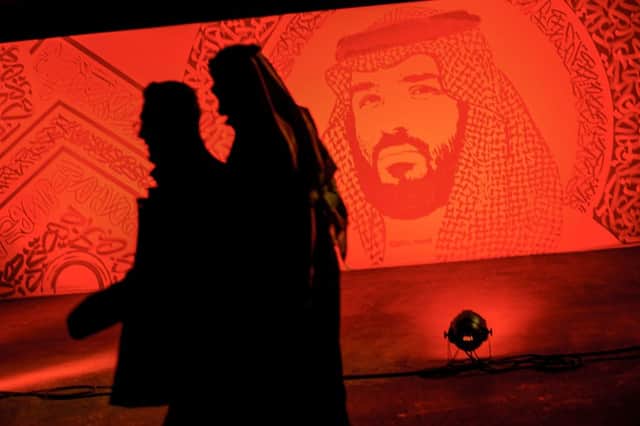 A picture taken on January 31, 2020 shows young Saudis walking next to a portrait of Crown Prince Mohammed bin Salman at the Riyadh Season Boulevard in the Saudi capital. 