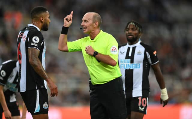Referee Mike Dean has words with Jamaal Lascelles during the Premier League match between Newcastle United and Leeds United at St. James Park on September 17, 2021 in Newcastle upon Tyne, England.