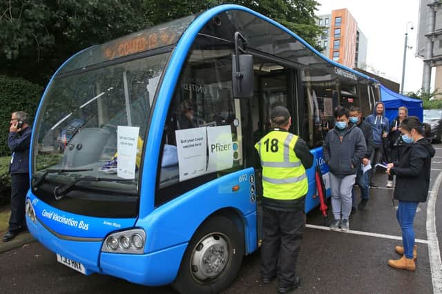 People queue to receive a dose of the Pfizer/BioNTech covid-19 vaccine at a mobile vaccination centre set up in a bus parked outside Premier League club Newcastle United’s St James’s Park football stadium in Newcastle, north east England on August 15, 2021. - The UK opens Covid-19 vaccination appointments to 16-19 year old, hoping that all in this age group are offered a dose of the vaccine by August 23.