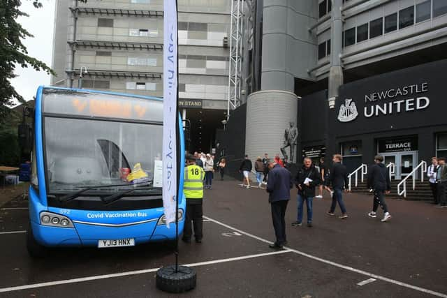 People queue to receive a dose of the Pfizer/BioNTech covid-19 vaccine at a mobile vaccination centre set up in a bus parked outside Premier League club Newcastle United’s St James’s Park football stadium in Newcastle, north east England on August 15, 2021. - The UK opens Covid-19 vaccination appointments to 16-19 year old, hoping that all in this age group are offered a dose of the vaccine by August 23.