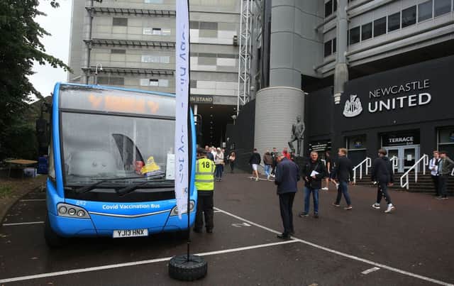 People queue to receive a dose of the Pfizer/BioNTech covid-19 vaccine at a mobile vaccination centre set up in a bus parked outside Premier League club Newcastle United’s St James’s Park football stadium in Newcastle, north east England on August 15, 2021. - The UK opens Covid-19 vaccination appointments to 16-19 year old, hoping that all in this age group are offered a dose of the vaccine by August 23.