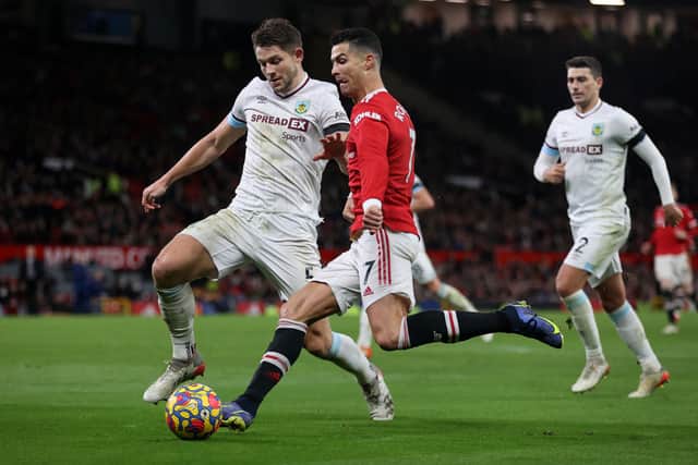 Cristiano Ronaldo of Manchester United is challenged by James Tarkowski of Burnley during the Premier League match between Manchester United and Burnley at Old Trafford on December 30, 2021 in Manchester, England.