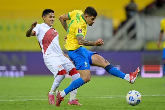 Bruno Guimares of Brazil kicks the ball against Alex Valera of Peru during a match between Brazil and Peru as part of South American Qualifiers for Qatar 2022 at Arena Pernambuco on September 09, 2021