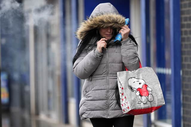 A woman pulls down her hat against the wind as the UK awaits the arrival of Storm Dudley.