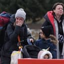 KORCZOWA, POLAND - MARCH 02: A distraught mother wipes tears as she and her children fleeing war-torn Ukraine wait to cross into Poland at the Korczowa crossing on March 02, 2022 near Korczowa, Poland. Women and children arrived at the crossing throughout the day, some tearful as many have left their fathers, husbands and grown sons behind. Ukraine authorities are forbidding men aged between 18 and 60 from leaving and calling on them to fight. More than 400, 000 people have crossed the border into Poland from Ukraine in the first week since Russia’s invasion. Meanwhile fighting is raging between the invading Russian military and Ukrainian armed forces across Ukraine. (Photo by Sean Gallup/Getty Images)