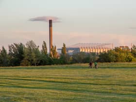 Friends cycle through Newcastle-Upon-Tyne’s Town Moor park with the impressive structure of St James Park football stadium looming large in the background.