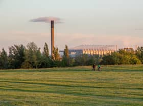 Friends cycle through Newcastle-Upon-Tyne’s Town Moor park with the impressive structure of St James Park football stadium looming large in the background.