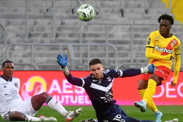 Lens’ French forward Arnaud Kalimuendo (R) and Bordeaux’s French goalkeeper Gaetan Poussin fight for the ball during the French L1 football match between RC Lens and Bordeaux at the Bollaert-Delelis stadium, in Lens, on February 13, 2022. 