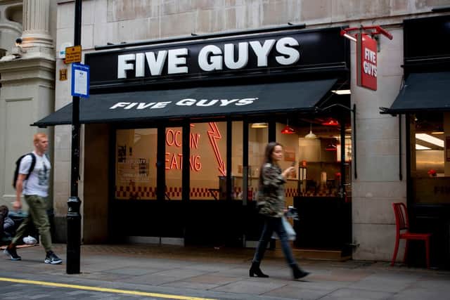 A pedestrian passes a Five Guys hamburger restaurant in central London on September 11, 2019. 