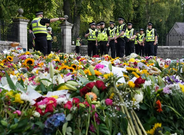 <p>Police officers arrive at the gates of Balmoral in Scotland where flowers and tributes have been laid by members of the public following the death of Queen Elizabeth II. The Queen's coffin will be transported on a six-hour journey from Balmoral to the Palace of Holyroodhouse in Edinburgh, where it will lie at rest. Picture date: Sunday September 11, 2022.</p>