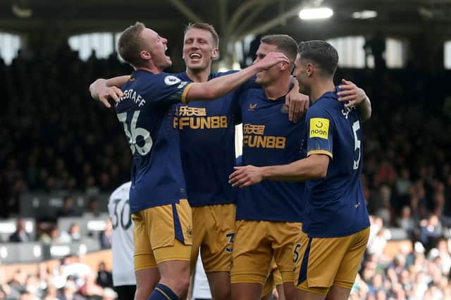 Sean Longstaff of Newcastle United celebrate with team mates Dan Burn, Sven Botman and Fabian Schar after scoring their sides third goal during the Premier League match between Fulham FC and Newcastle United at Craven Cottage on October 01, 2022 in London, England.