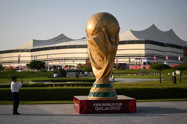 A man takes a picture of a FIFA World Cup trophy replica in front of the Al-Bayt Stadium in al-Khor on November 10, 2022, ahead of the Qatar 2022 FIFA World Cup football tournament. 