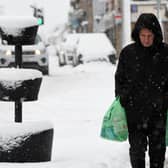 A pedestrian carries their shopping through the snow in Auchterarder, central Scotland, on February 18, 2022, as Storm Eunice brings high winds across the country.