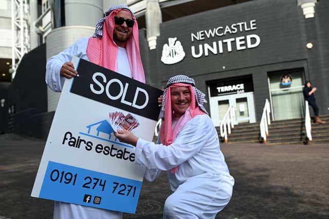 Newcastle United supporters dressed in robes pose with 'sold' placards as they celebrate the sale of the club to a Saudi-led consortium, outside the club's stadium at St James' Park in Newcastle upon Tyne in northeast England on October 8, 2021.