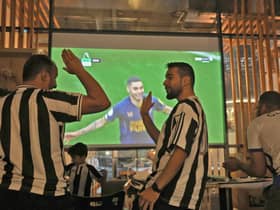 Saudi fans of English football club Newcastle United celebrate a goal scored against Tottenham during as they watch the match at a cafe, in Riyadh on October 23, 2022. - The Saudi purchase of Newcastle - its sovereign wealth fund paid $408 million for an 80 percent stake - has proved deeply controversial, with critics quick to deride it as an example of “sportswashing”, or using athletics to distract from human rights abuses.The takeover was rubber-stamped by the Premier League only after it received legally binding assurances the Saudi state would not control the team. (Photo by Fayez Nureldine / AFP) (Photo by FAYEZ NURELDINE/AFP via Getty Images)