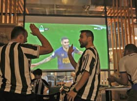 Saudi fans of English football club Newcastle United celebrate a goal scored against Tottenham during as they watch the match at a cafe, in Riyadh on October 23, 2022. - The Saudi purchase of Newcastle - its sovereign wealth fund paid $408 million for an 80 percent stake - has proved deeply controversial, with critics quick to deride it as an example of “sportswashing”, or using athletics to distract from human rights abuses.The takeover was rubber-stamped by the Premier League only after it received legally binding assurances the Saudi state would not control the team. (Photo by Fayez Nureldine / AFP) (Photo by FAYEZ NURELDINE/AFP via Getty Images)