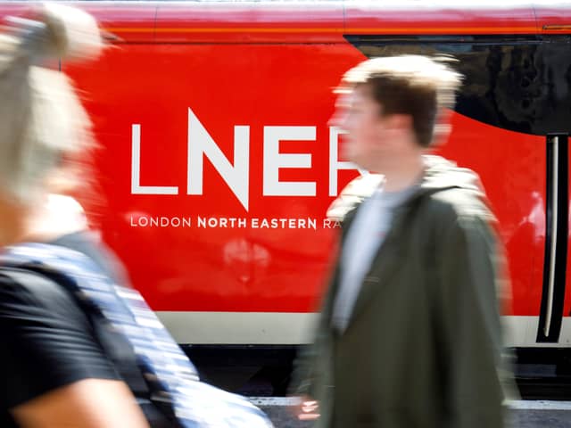 A passenger passes a London North Eastern Railway (LNER) train at King’s Cross rail station in London on June 25, 2018, during a photocall for the re-launch of the rail service on the East Coast mainline. - The LNER service was relaunched Monday after Britain’s Transport Secretary Chris Grayling announced last month he would bring the franchise back under public control and terminate the franchise with Virgin Trains East Coast (VTEC), which had overbid and made a loss. The East Coast railway line -- which links London with Durham, Leeds, York, Newcastle and Edinburgh -- was awarded to Virgin Trains East Coast (VTEC) three years ago in a Â£3.3-billion franchise contract initially due to run until 2023. (Photo by Tolga Akmen / AFP)        (Photo credit should read TOLGA AKMEN/AFP via Getty Images)