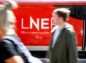 A passenger passes a London North Eastern Railway (LNER) train at King’s Cross rail station in London on June 25, 2018, during a photocall for the re-launch of the rail service on the East Coast mainline. - The LNER service was relaunched Monday after Britain’s Transport Secretary Chris Grayling announced last month he would bring the franchise back under public control and terminate the franchise with Virgin Trains East Coast (VTEC), which had overbid and made a loss. The East Coast railway line -- which links London with Durham, Leeds, York, Newcastle and Edinburgh -- was awarded to Virgin Trains East Coast (VTEC) three years ago in a Â£3.3-billion franchise contract initially due to run until 2023. (Photo by Tolga Akmen / AFP)        (Photo credit should read TOLGA AKMEN/AFP via Getty Images)