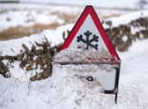 An ice warning sign is covered with snow.