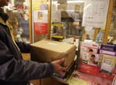 Customers weigh packages at the post office.