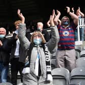 A Newcastle fan  wearing a face covering applauds the players as they enter the field during the Premier League match between Newcastle United and Sheffield United at St. James Park on May 19, 2021.