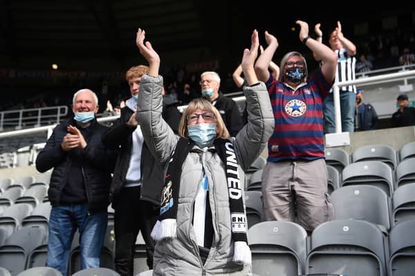 A Newcastle fan  wearing a face covering applauds the players as they enter the field during the Premier League match between Newcastle United and Sheffield United at St. James Park on May 19, 2021.