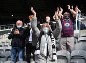 A Newcastle fan  wearing a face covering applauds the players as they enter the field during the Premier League match between Newcastle United and Sheffield United at St. James Park on May 19, 2021.