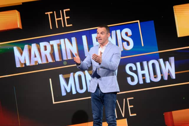 Martin Lewis pictured on set of The Martin Lewis Money Show, gesturing to the audience with his logo behind him (Credit: Multistory Media/Jonathan Hordle/ITV)