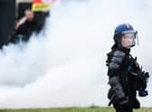 A French gendarme stands next to smoke during a demonstration as part of a national day of strikes and protests, a week after the French government pushed a pensions reform through parliament without a vote, using the article 49.3 of the constitution, in Nantes, western France, on March 23, 2023