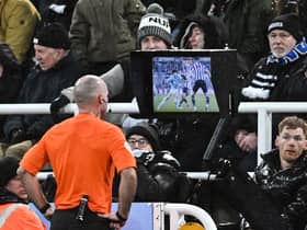 Referee Paul Tierney makes a VAR check in front of Newcastle fans