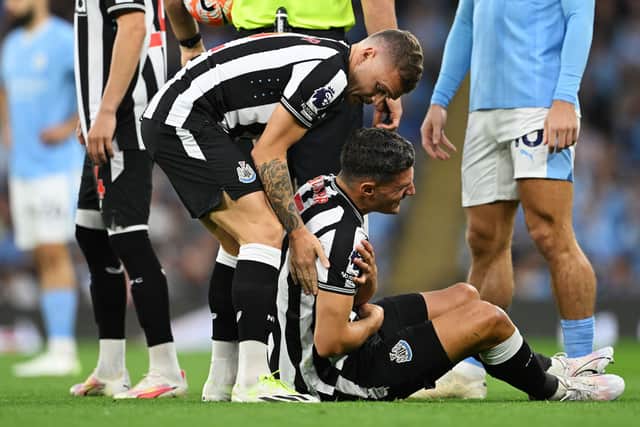Fabian Schar of Newcastle United is comforted by teammate Kieran Trippier after going down with an injury during the Premier League match between Manchester City and Newcastle United at Etihad Stadium on August 19, 2023 in Manchester, England. 