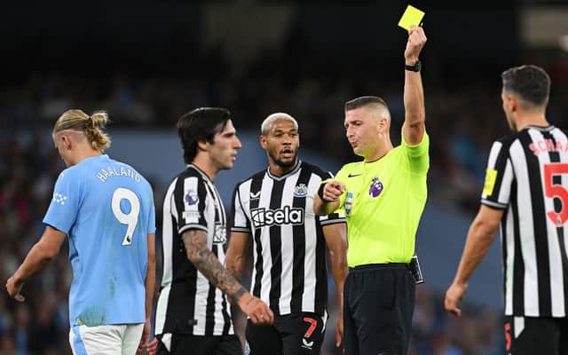 Robert Jones shows a yellow card to Sandro Tonali of Newcastle United during the Premier League match between Manchester City and Newcastle United at Etihad Stadium on August 19, 2023 in Manchester, England.