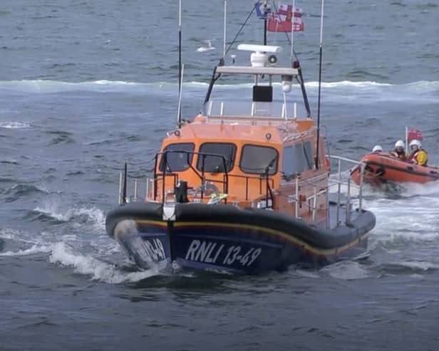 Dolphins swim alongside RNLI lifeboat in Whitby, North Yorkshire. 