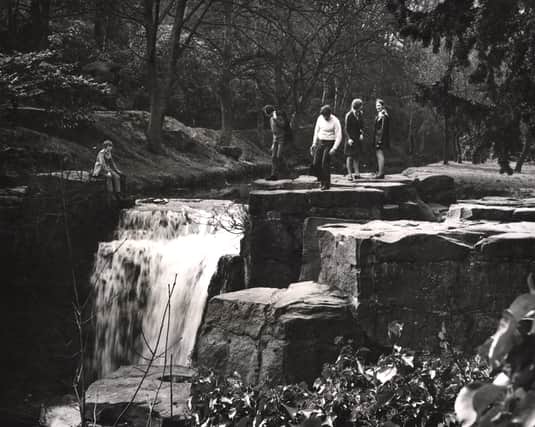 : A view of Jesmond Dene Newcastle upon Tyne taken in 1972. The photograph taken from the bridge shows a group of people standing on the rocks at the top of the waterfall (Newcastle Libraries)
