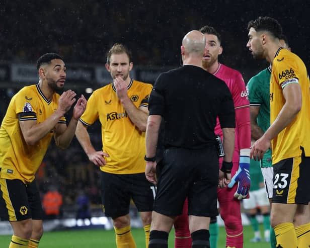 Wolves players appeal to English referee Anthony Taylor as the VAR (Video Assistant Referee) analyses a possible penalty offence during the English Premier League football match between Wolverhampton Wanderers and Newcastle United at the Molineux stadium in Wolverhampton, central England on October 28, 2023. (Photo by Adrian DENNIS / AFP)