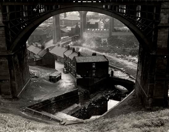 A view of Ouseburn Road Byker taken in 1960. The photograph is framed by an arch of the Ouseburn Viaduct and shows the Flint Mill Cottages and the Ouseburn Cottages on the Ouseburn Road. The arches of Byker Bridge can be seen in the background.