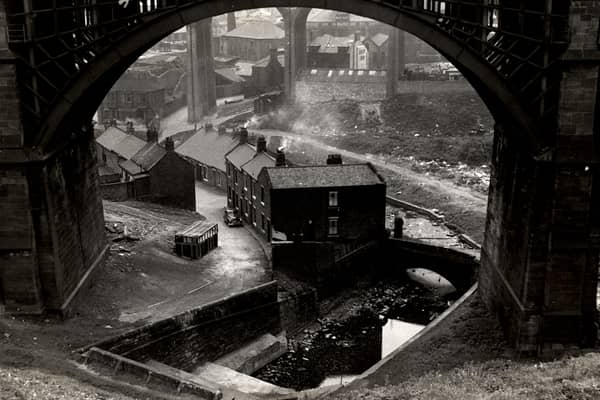 A view of Ouseburn Road Byker taken in 1960. The photograph is framed by an arch of the Ouseburn Viaduct and shows the Flint Mill Cottages and the Ouseburn Cottages on the Ouseburn Road. The arches of Byker Bridge can be seen in the background.