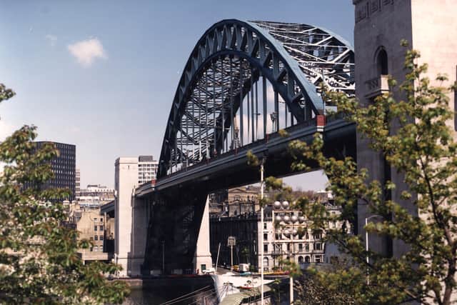 A colour photographic print showing the Tyne Bridge from Gateshead Quayside. The tall black building on the left-hand side of the picture is Cale Cross House.