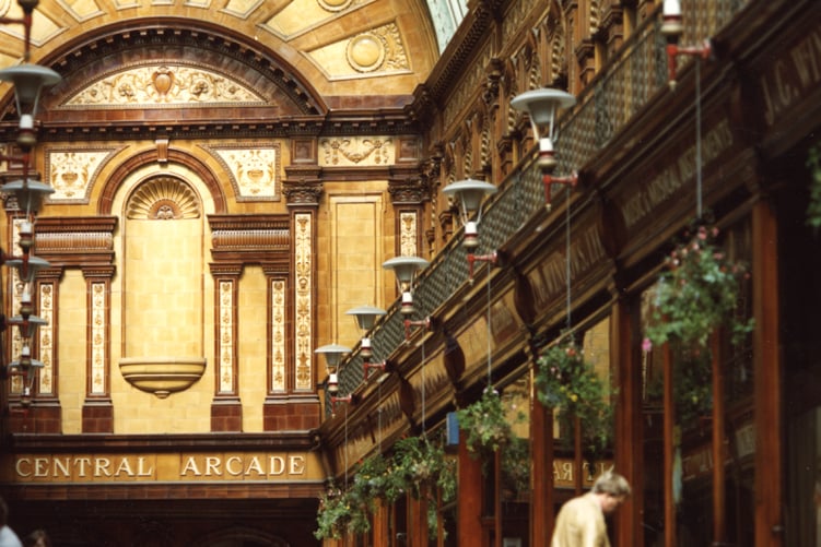 A view of the Central Arcade Newcastle upon Tyne taken in 1982. The photograph shows the interior of the Central Arcade which is decorated with Burmantofts tiles in shades of brown buff and yellow. 'J. G. Windows Ltd' music store is to the right. 