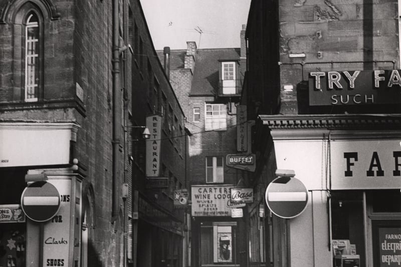 The picture shows the length of Nun's Lane running from Newgate Street in the foreground to Nun's Street in the background. At the centre back of the picture is Carter's Wine Lodge. To the front right is Farnono's Electriconical Department. 
