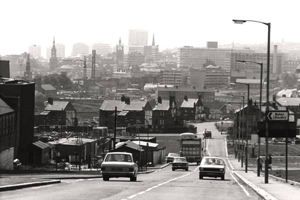 A view of Byker taken in 1974. The photograph is looking towards Newcastle city centre. Buildings are in the process of being demolished on both sides of the road. The towers of St. Nicholas Cathedral All Saints Church and St. Ann's Church can be seen among the buildings in the background.
