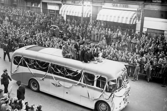 A photograph of a bus containing Newcastle United players and the FA Cup taken in 1952. The team have returned to Newcastle after winning the F.A. Cup and are processing through the streets.