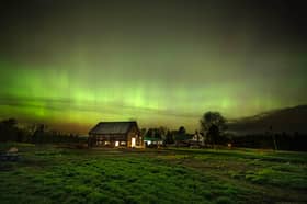 The northern lights fill the sky with green ribbons of electrical charged particles over a barn (Photo by Michael Seamans/Getty Images)