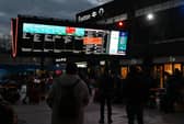 Rail travellers look at an electronic information board displaying train time information outside Euston Station in London. Photo: JUSTIN TALLIS/AFP via Getty Images
